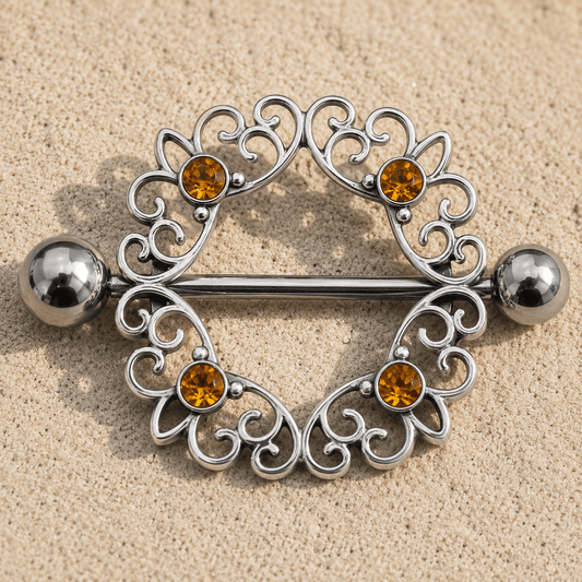 Close up of four round topaz CZ gems on ornate circular nipple shield, 316L stainless steel zinc alloy detail