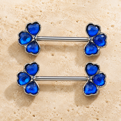 Pair of blue nipple barbels on a beige background