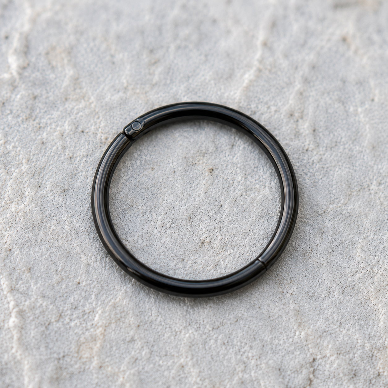 Close up of black PVD plating on titanium seamless clicker ring, matte finish detail 16G