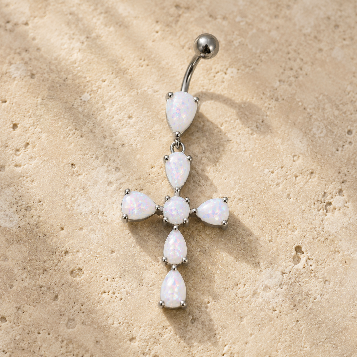 Belly button ring with opal stones on a beige stone background