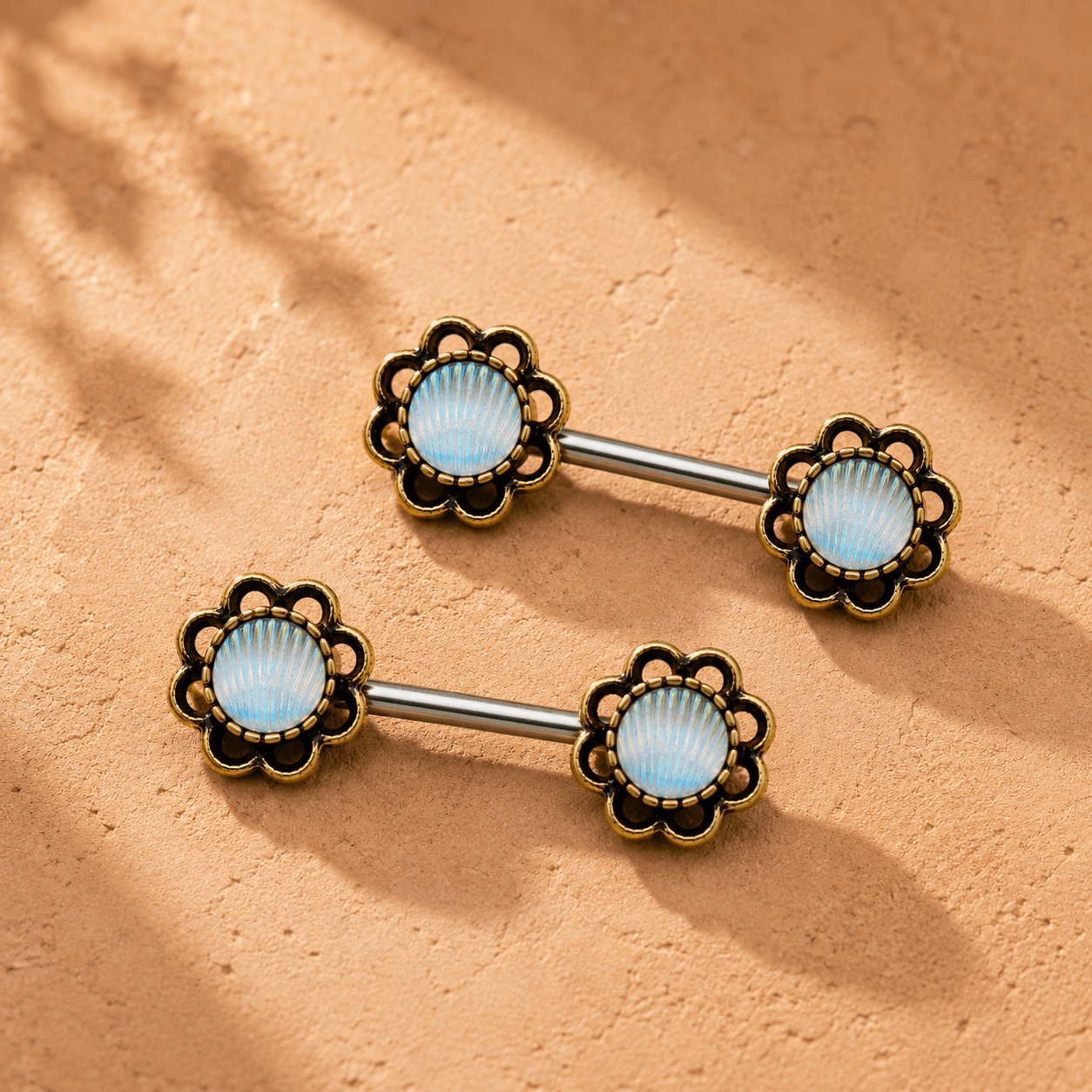 Pair of seashell themed barbell piercings on a beige background