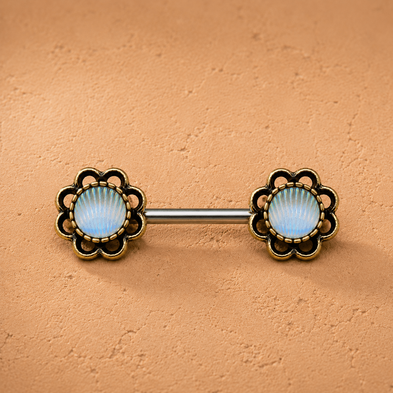Belly button ring with floral design and gemstone on a beige background