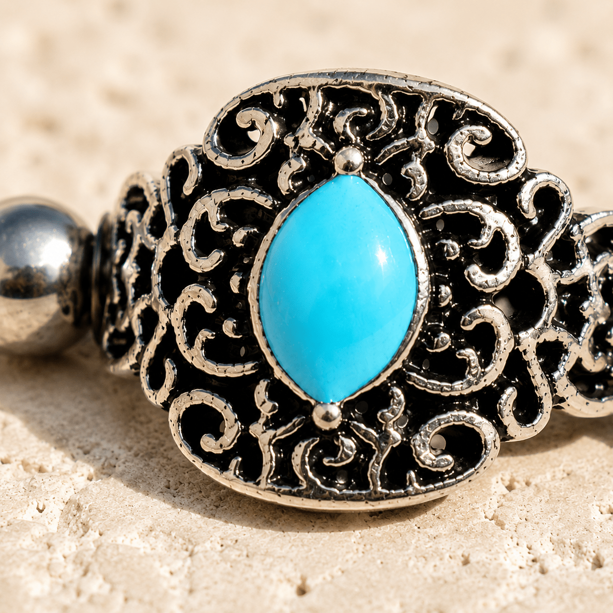 Close up of oval aqua enamel on ornate cartilage cuff earring, partial black plated zinc alloy detail
