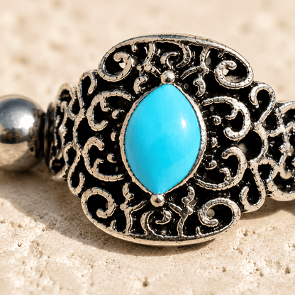 Close up of oval aqua enamel on ornate cartilage cuff earring, partial black plated zinc alloy detail
