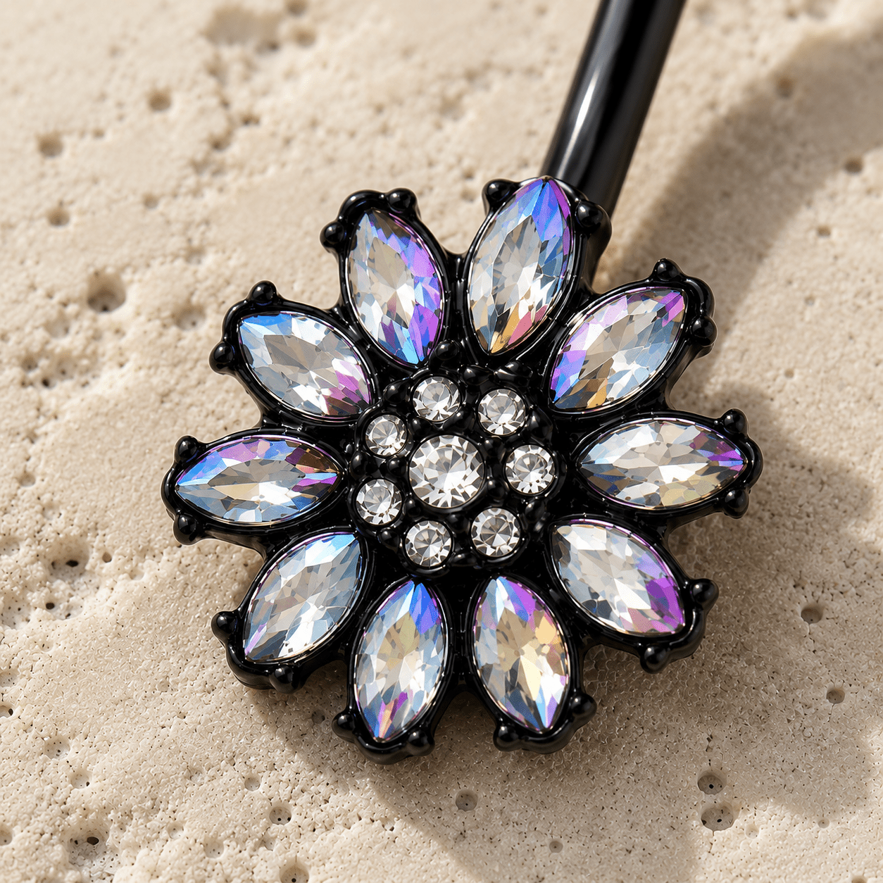 Belly button ring charm with rhinestone-like stones on a sandy background