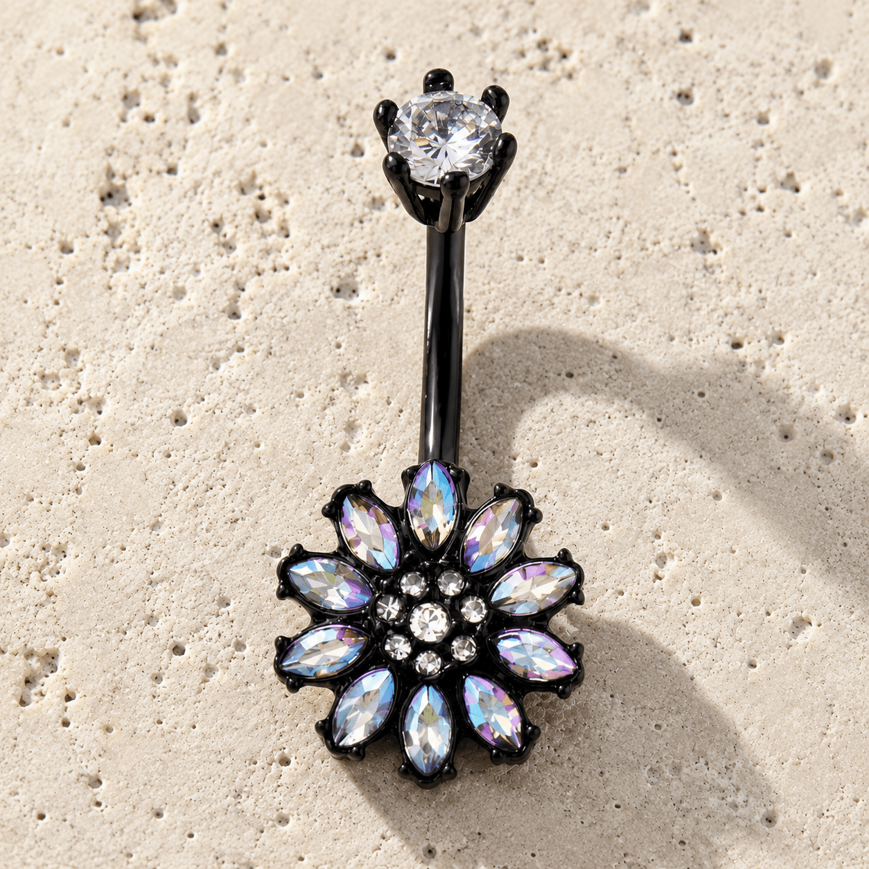 Belly button ring with floral design and gemstones on a beige surface