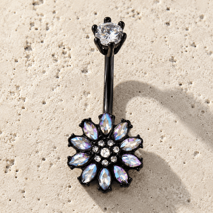 Belly button ring with floral design and gemstones on a beige surface