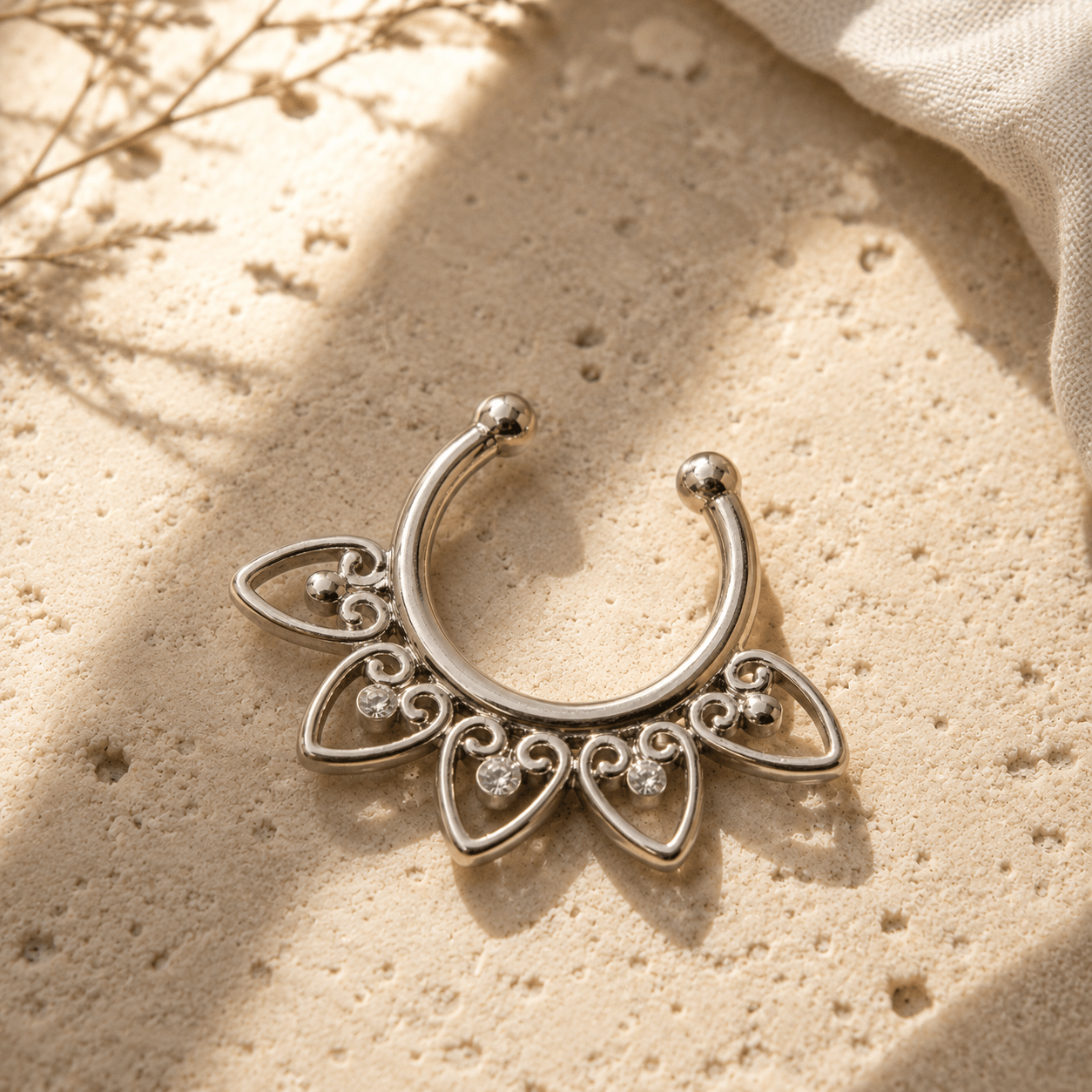Ornamental hearts fake septum ring flat lay on sand, boho clip-on nose ring, silver stainless steel CZ gems