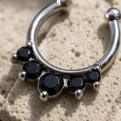 Close up of five black cubic zirconia gems on princess fake septum ring, polished stainless steel detail