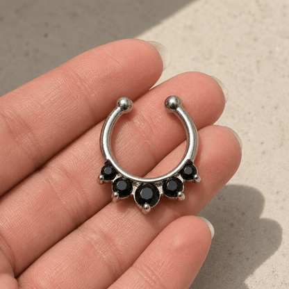 Hand holding gemmed princess fake septum ring, black CZ clip-on nose ring, 316L stainless steel