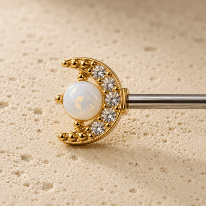 Close up of crescent moon CZ and white opal star on gold nipple bar, celestial detail