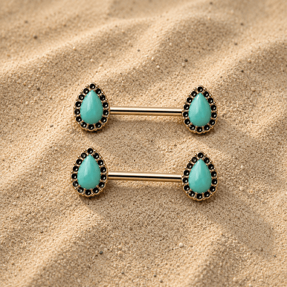 Pair of gold nipple ring bars with turquoise stones on a sandy background