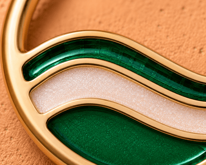 Close up of green and metallic white glitter enamel wave design on gold plated seamless ring detail
