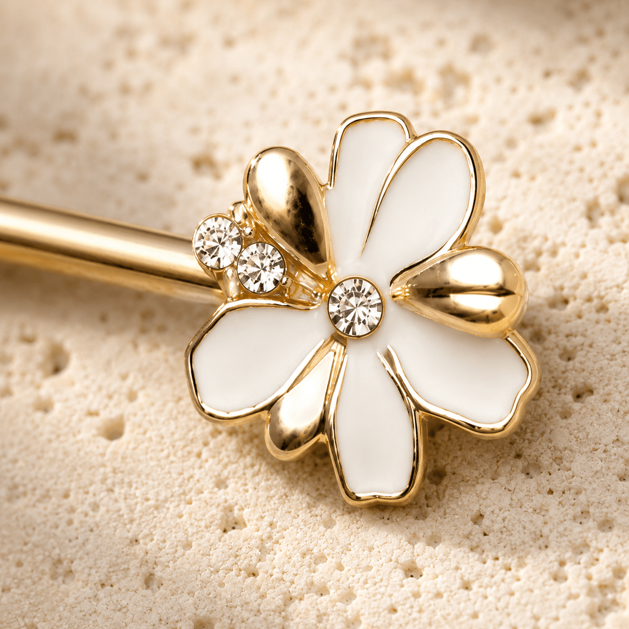 Close up of white enamel clear CZ flower on gold plated jeweled nipple bar, yellow gold plated zinc alloy detail