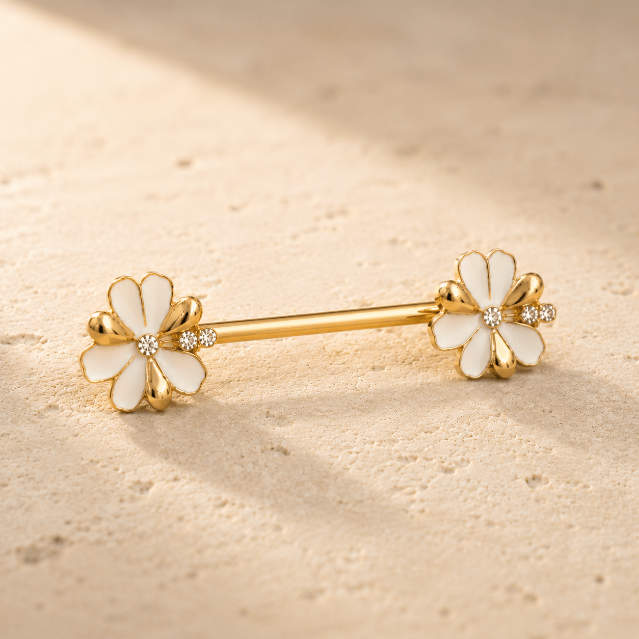 Styled aesthetic flat lay of gold plated jeweled white flower nipple bar pair, feminine floral CZ yellow gold body jewelry