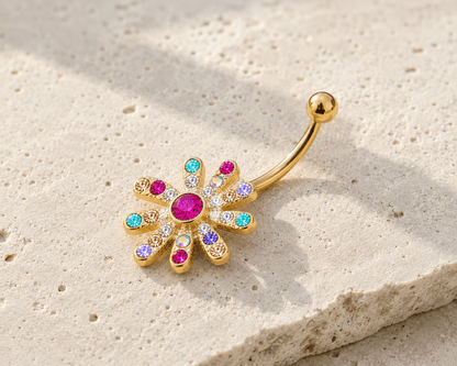 Gold belly button ring with colorful gemstones on a beige stone surface