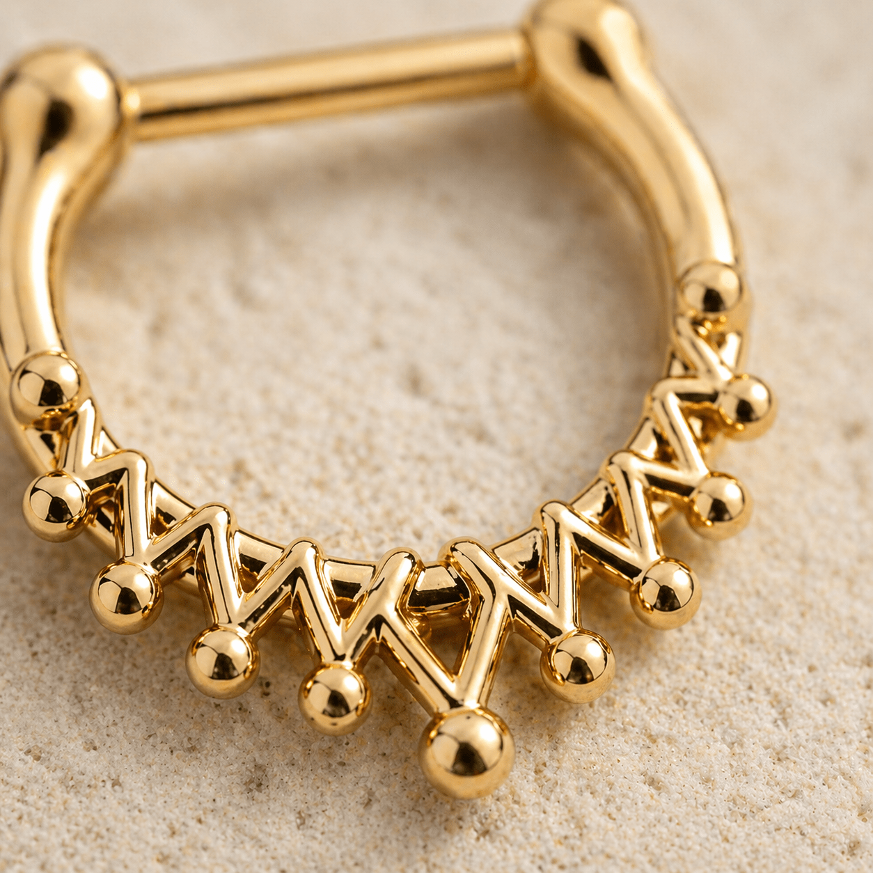 Close up of royal crown design on gold plated septum clicker, intricate detail, yellow gold finish