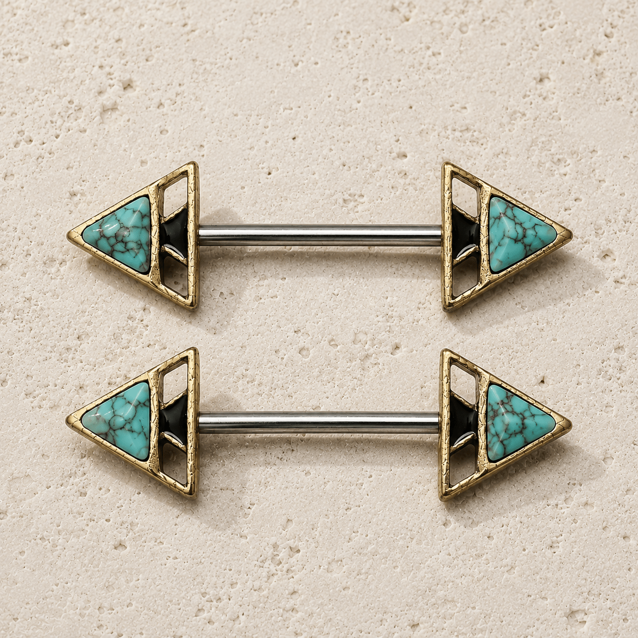 Pair of gold and turquoise triangle nipple barbell rings on a beige background