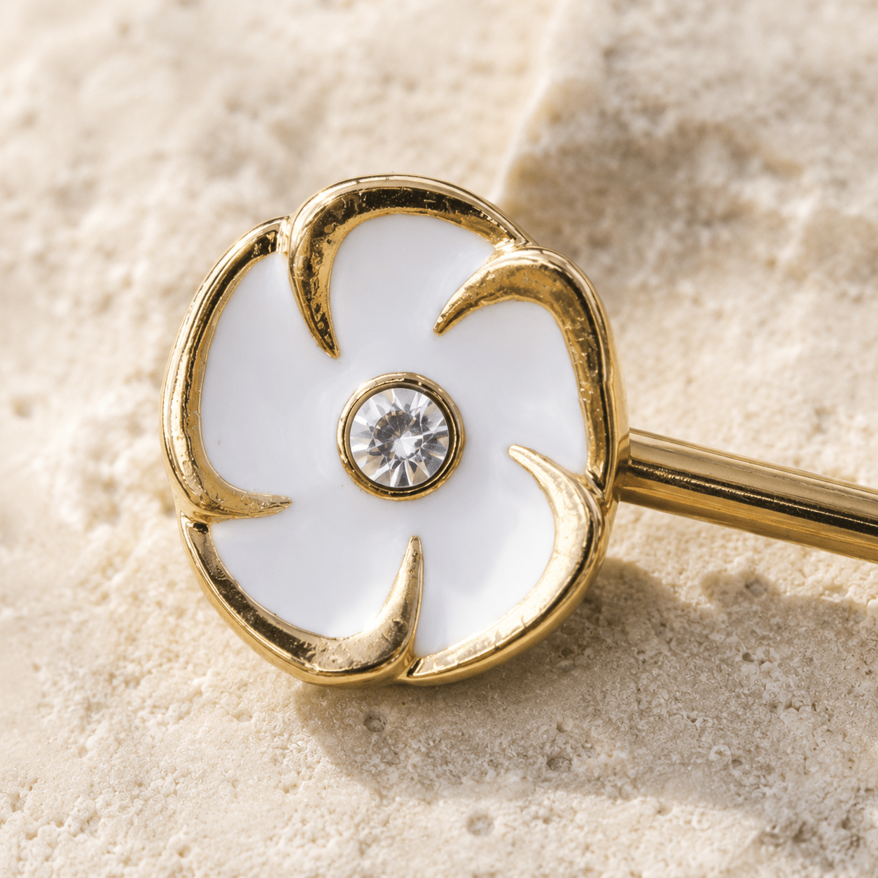 Close up of white enamel flower clear CZ center on gold plated nipple bar, yellow gold zinc alloy detail