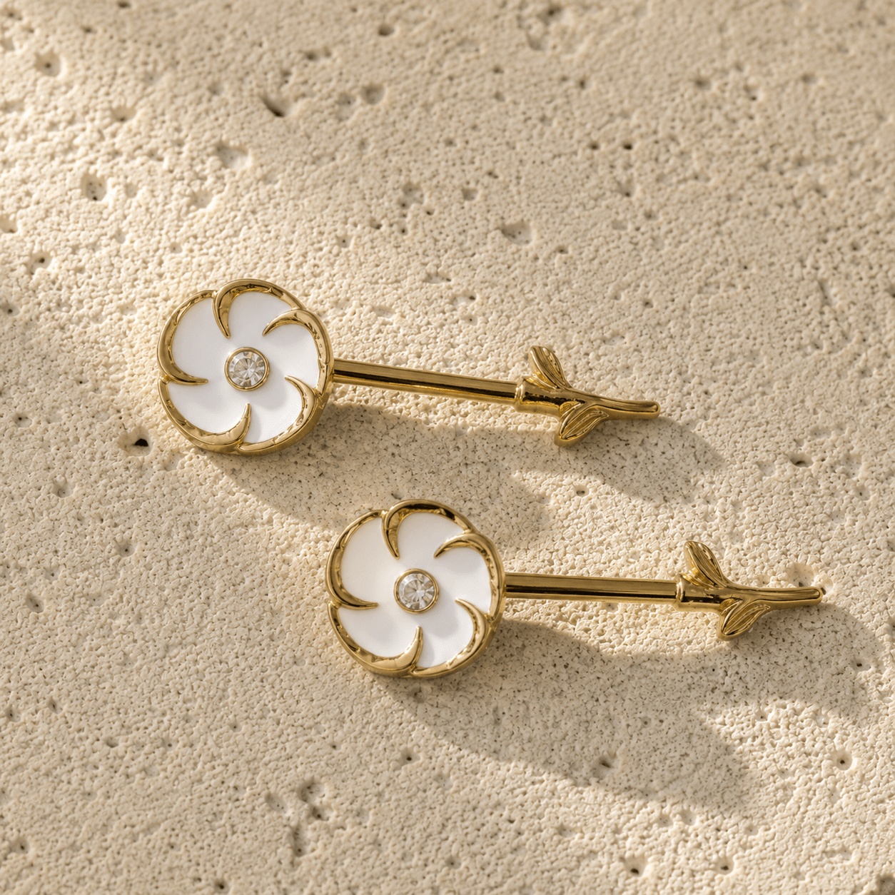 Styled aesthetic flat lay of gold plated white flower nipple bar pair, feminine floral yellow gold body jewelry