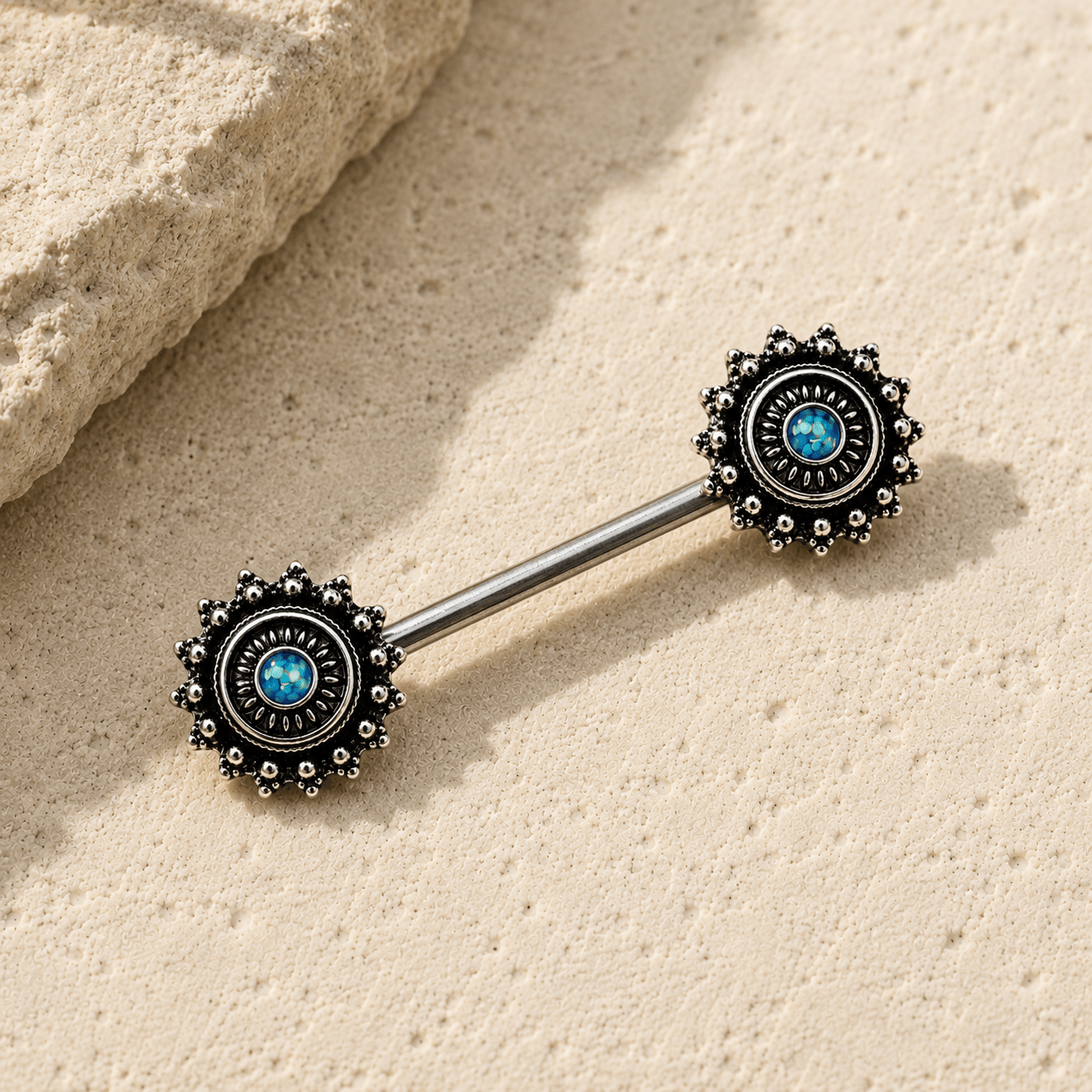 Styled flat lay of green opal ornate nipple bar pair, dark mystical black plated body jewelry
