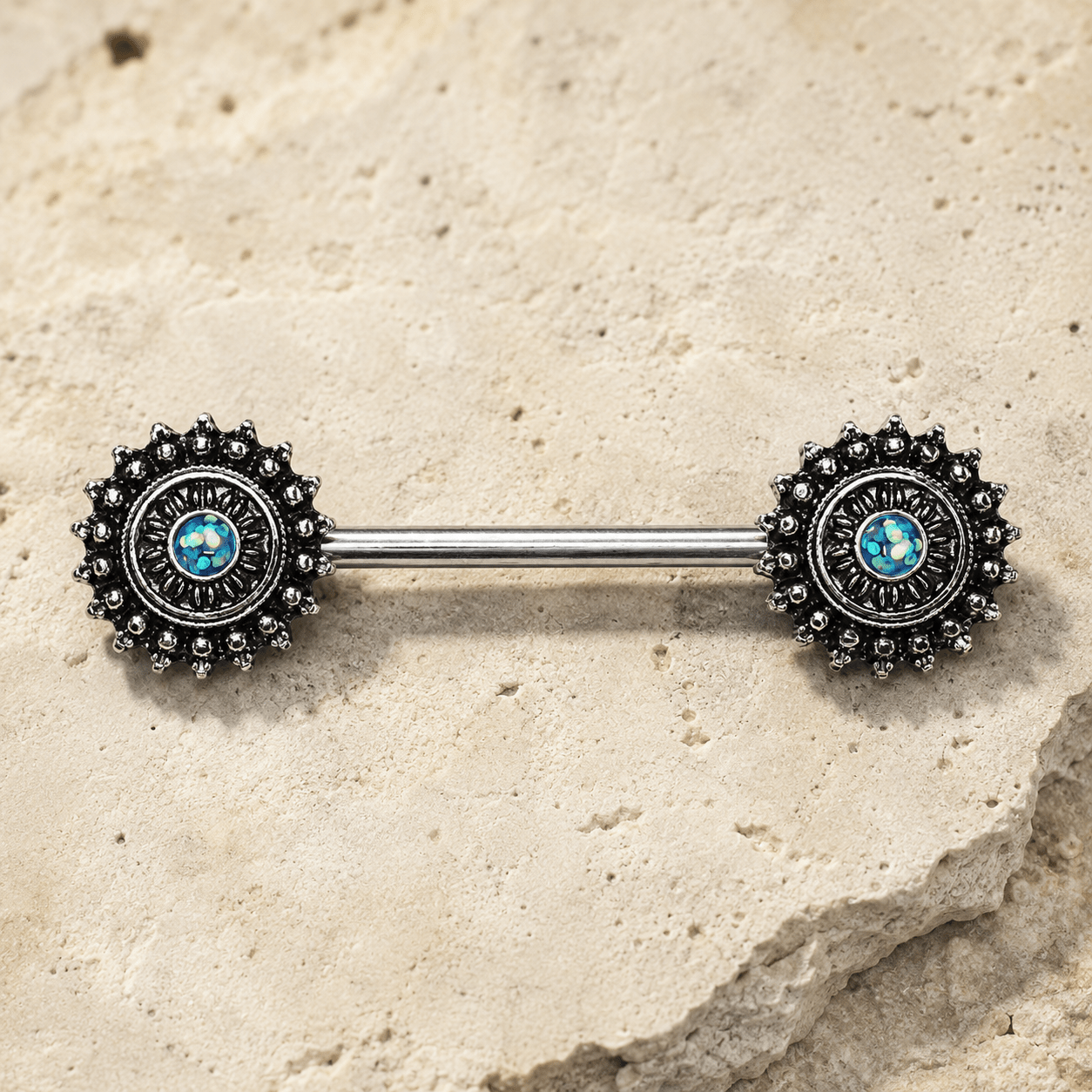 Metallic Nipple  barbell with decorative ends on a stone surface