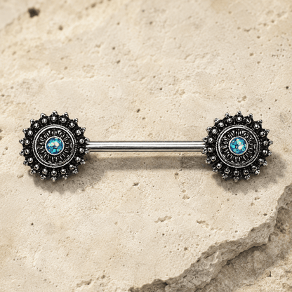 Metallic Nipple  barbell with decorative ends on a stone surface