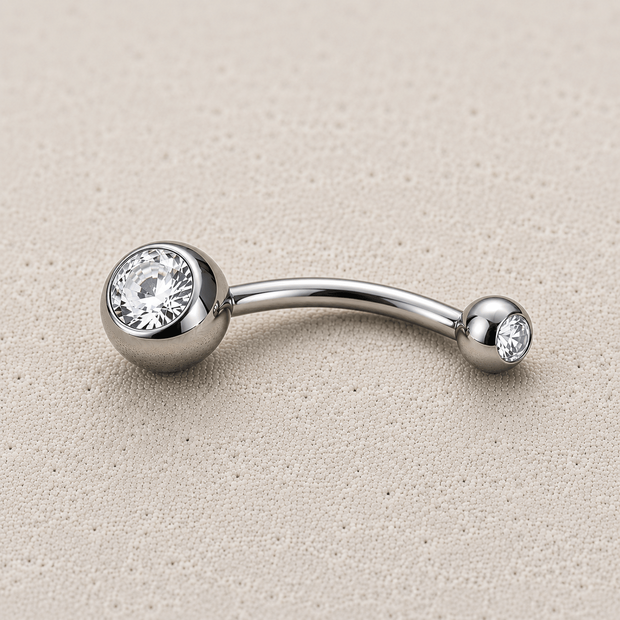 Silver belly button ring with two clear gemstones on a beige background