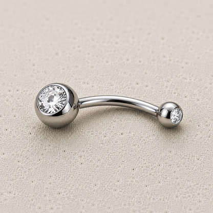 Silver belly button ring with two clear gemstones on a beige background
