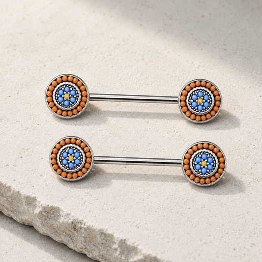 Two metallic nipple barbells with blue and orange bead designs on a stone surface.