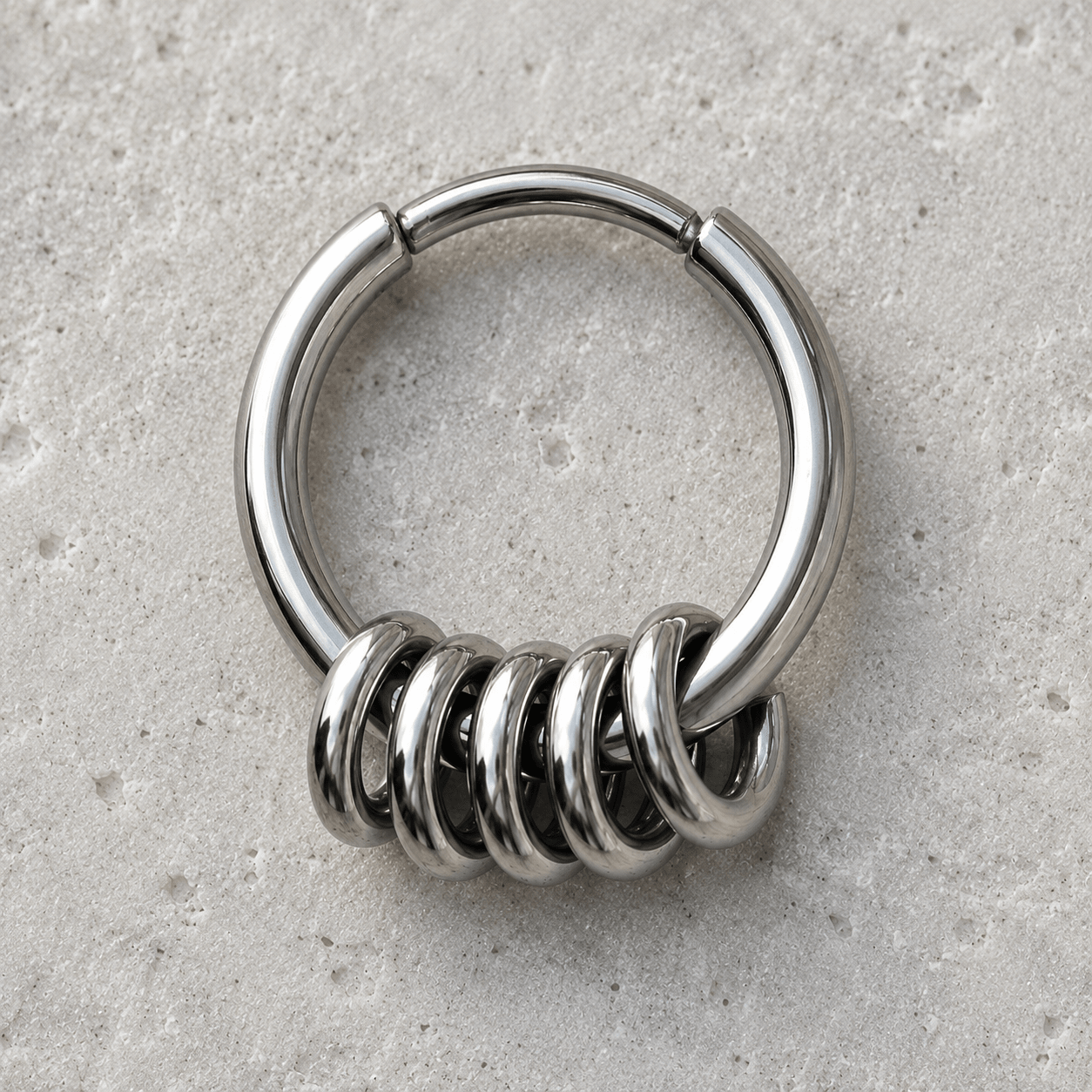 Metallic clicker ring with spiral design on a gray surface