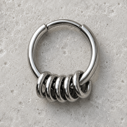 Metallic clicker ring with spiral design on a gray surface