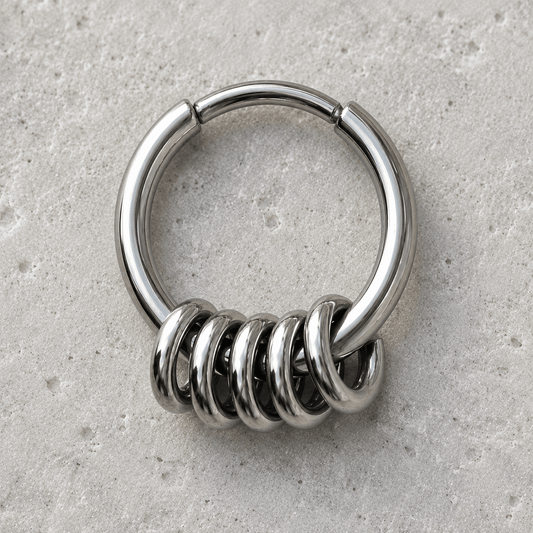 Metallic clicker ring with spiral design on a gray surface