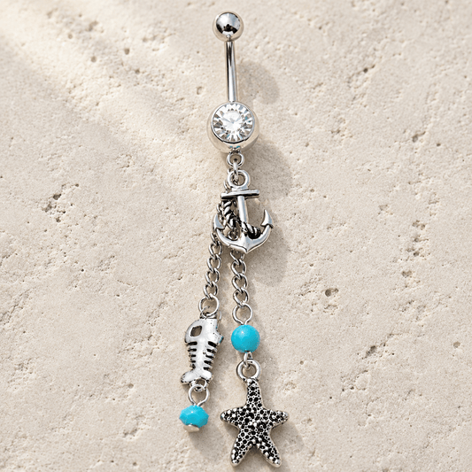 Belly button ring with starfish, fish, and turquoise bead charms on a beige background