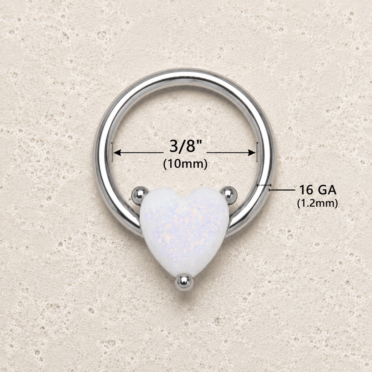 Heart-shaped white opal ring with measurements on a beige background