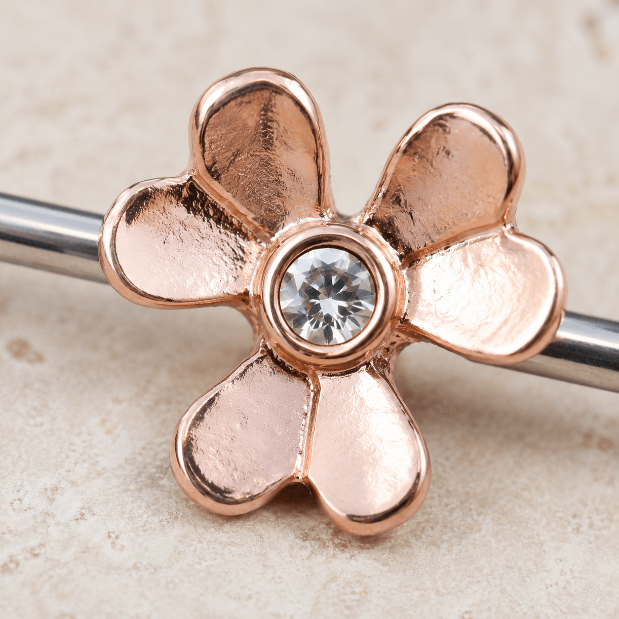 Close up of rose gold plated clover leaf with clear CZ gems on nipple bar, gold plated zinc alloy detail