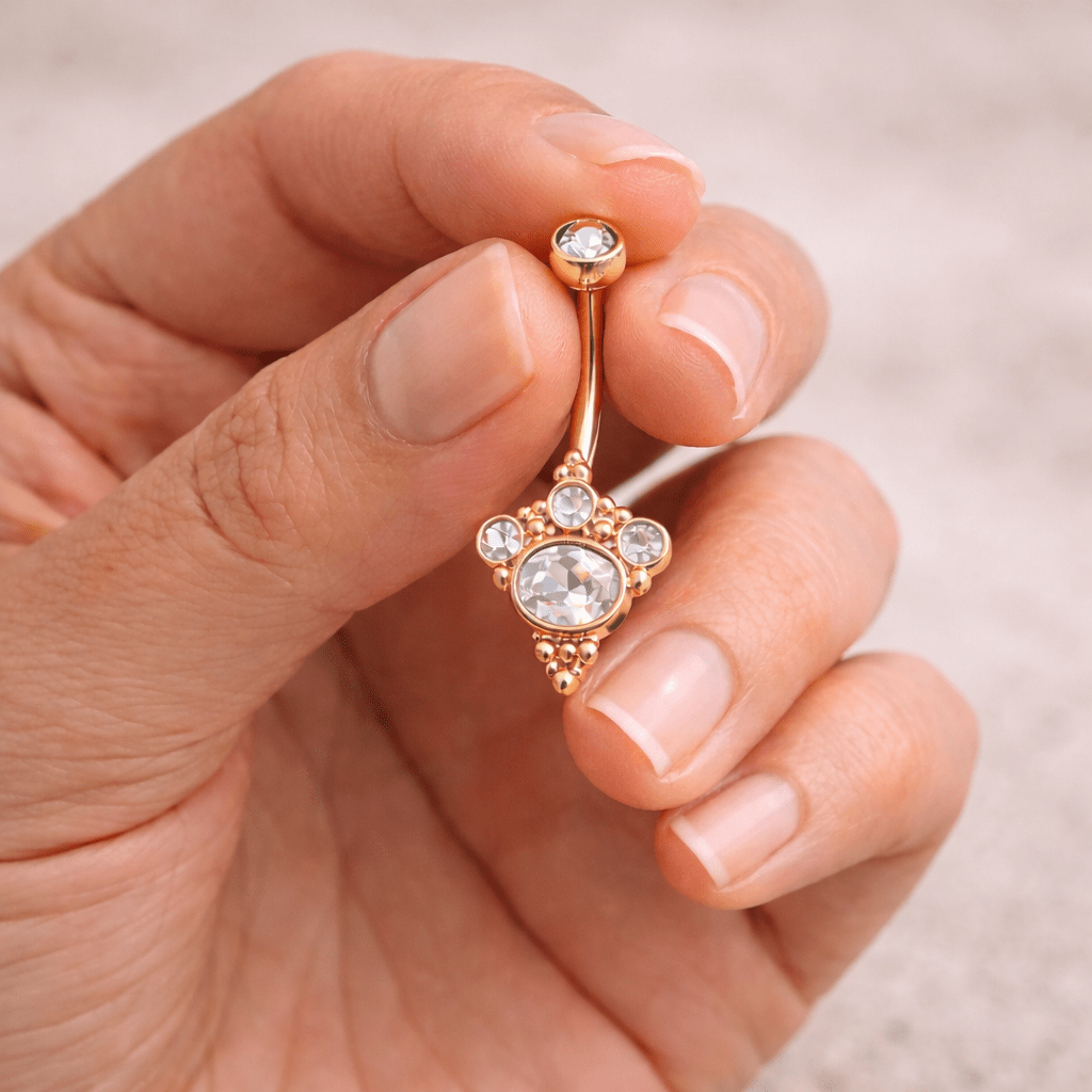 Hand holding rose gold Victorian navel ring, 14G clear CZ belly button ring, rose gold plated stainless steel

