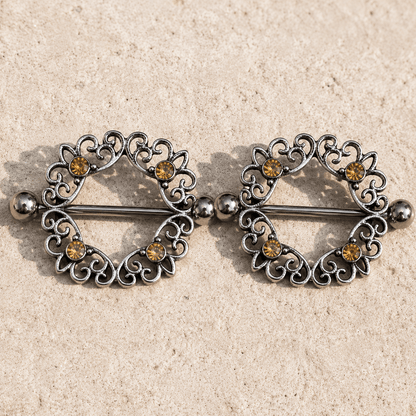 Styled aesthetic flat lay of topaz CZ ornate nipple shield pair, warm amber gemstone body jewelry 316L stainless steel