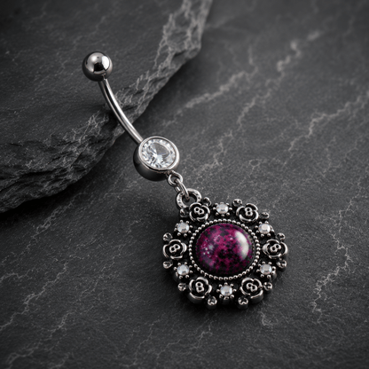 Decorative belly button ring with purple gemstone on a dark stone surface