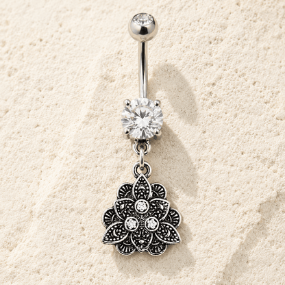 Silver belly button ring with floral pendant on a beige sand background