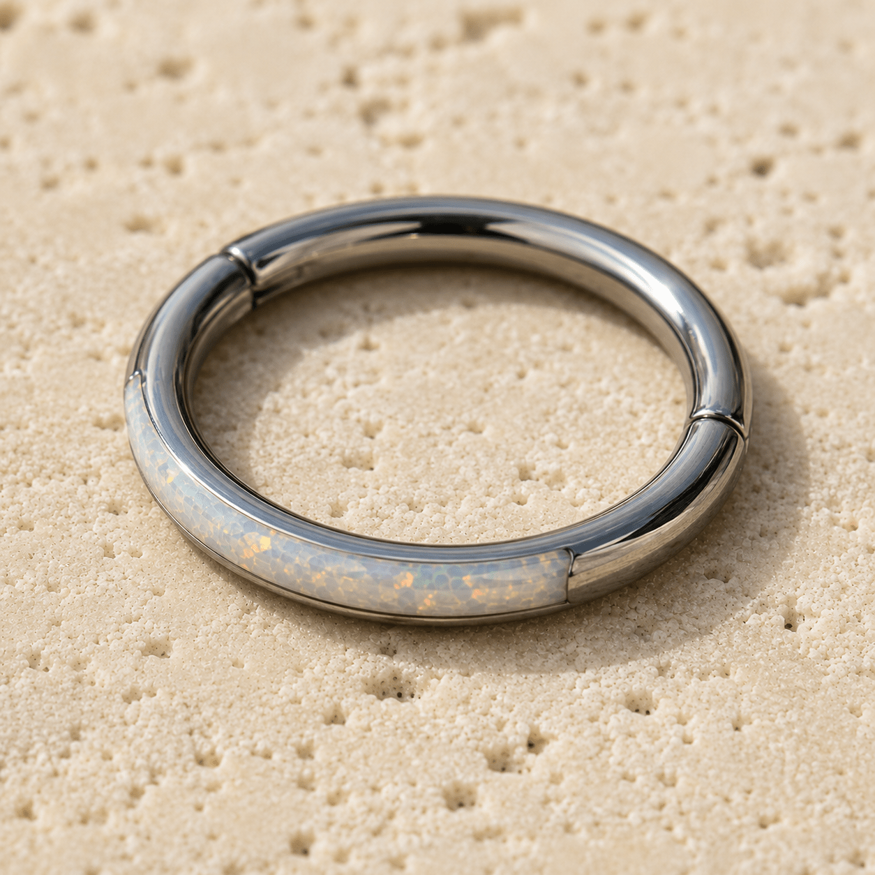 seamless clicker ring with opal inlay on a beige textured surface