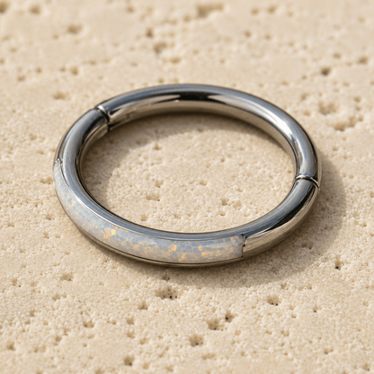 seamless clicker ring with opal inlay on a beige textured surface