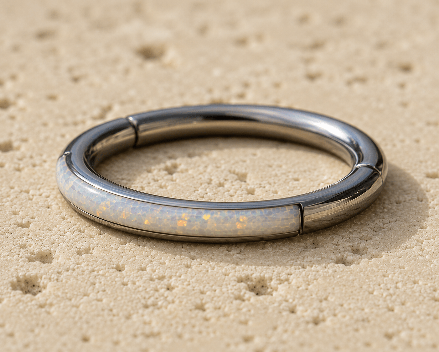 opal clicker ring with a glowing interior on a sandy surface