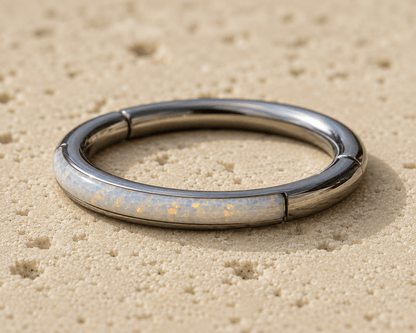 opal clicker ring with a glowing interior on a sandy surface